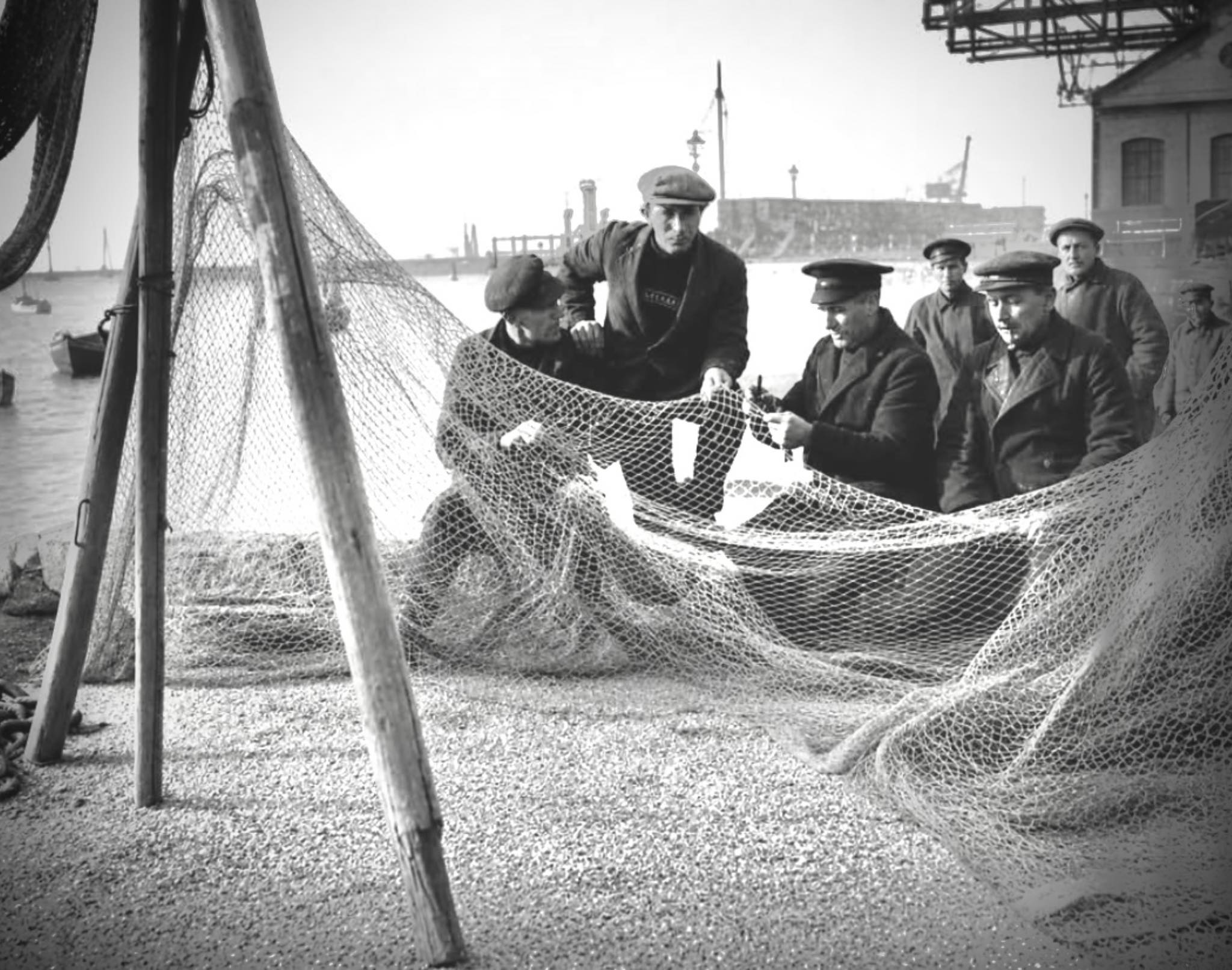Fishermen mending nets at Poole Quay in 1930s Dorset
