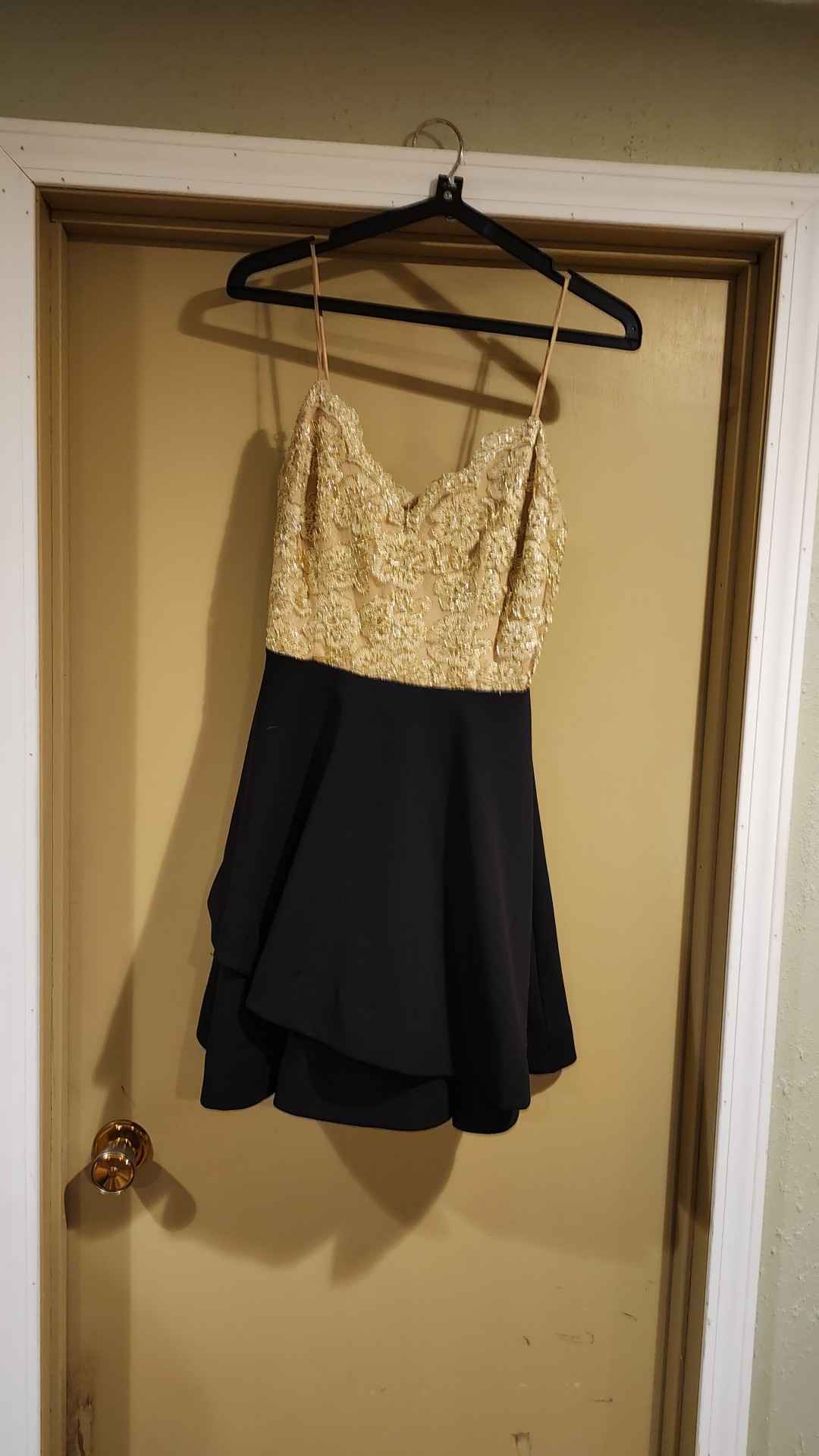 Elegant B. Darlin dress is a size 7/8. The bodice has gold floral embroidery over a tan lining with adjustable spaghetti straps. The skirt is a solid black, layered fit-and-flare style. The