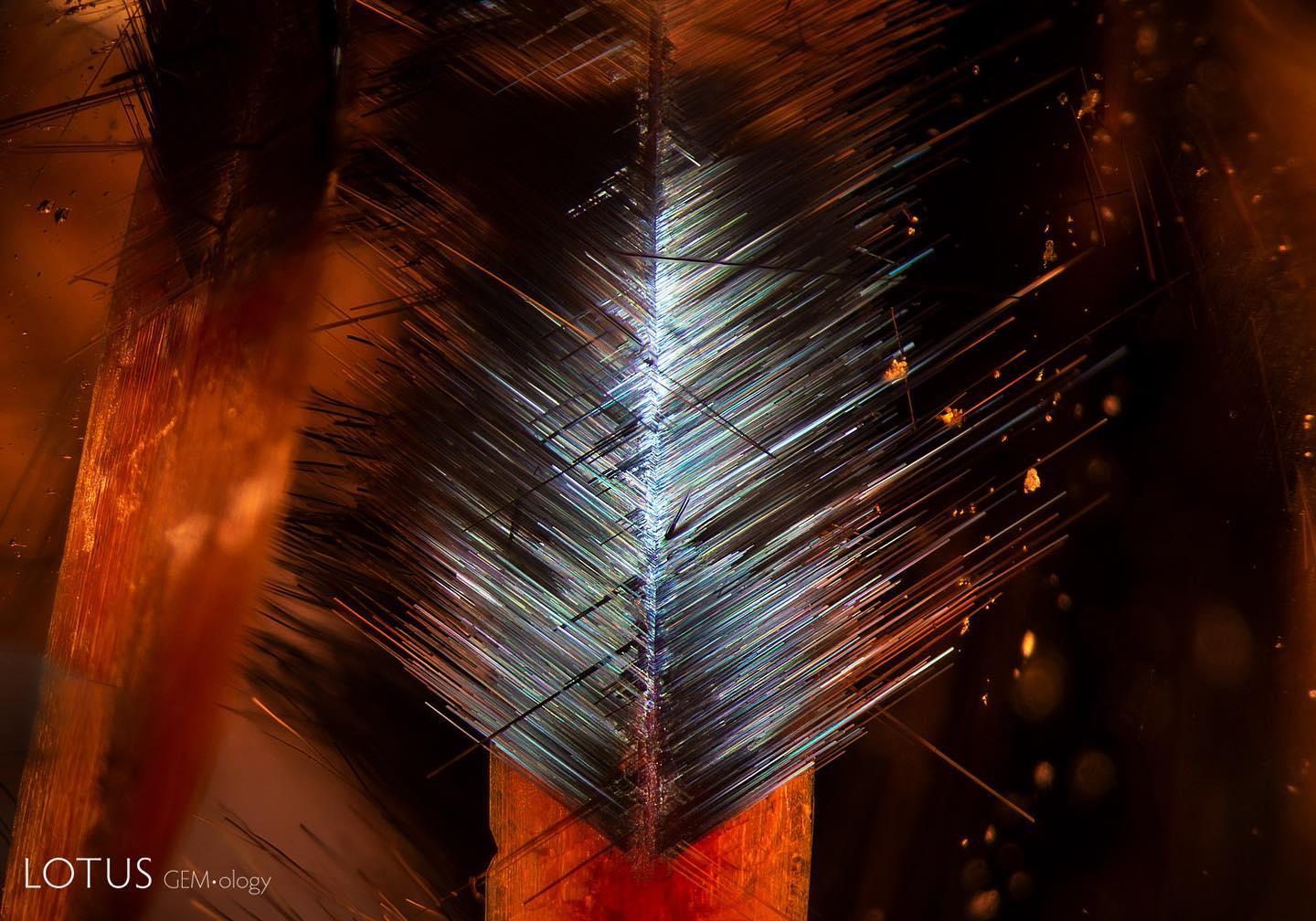 Lotus Gemology - Iridescent, needle-like inclusions form a...