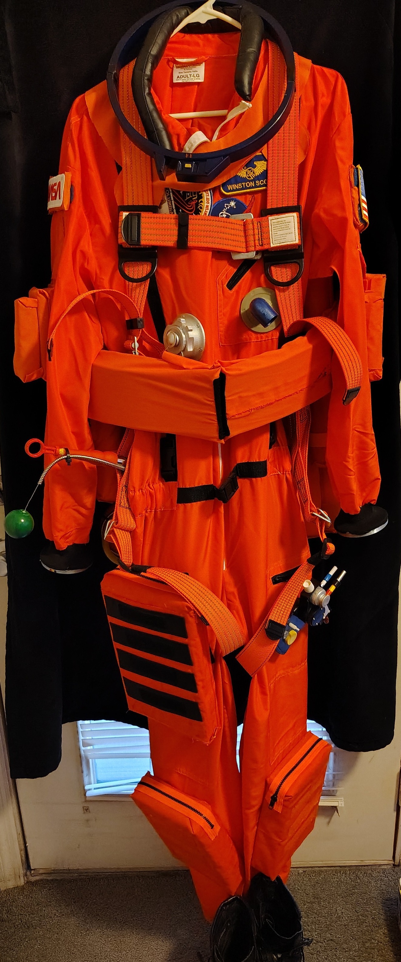 Space suit mock-up with orange safety harness and helmet