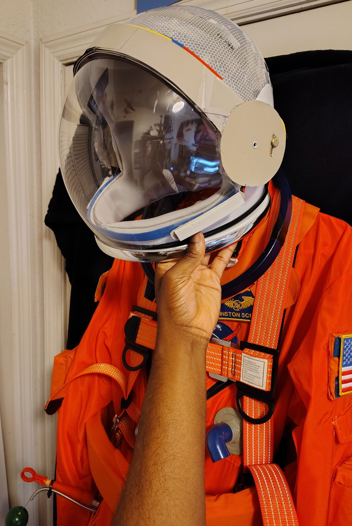 Space suit mock-up with orange safety harness and helmet