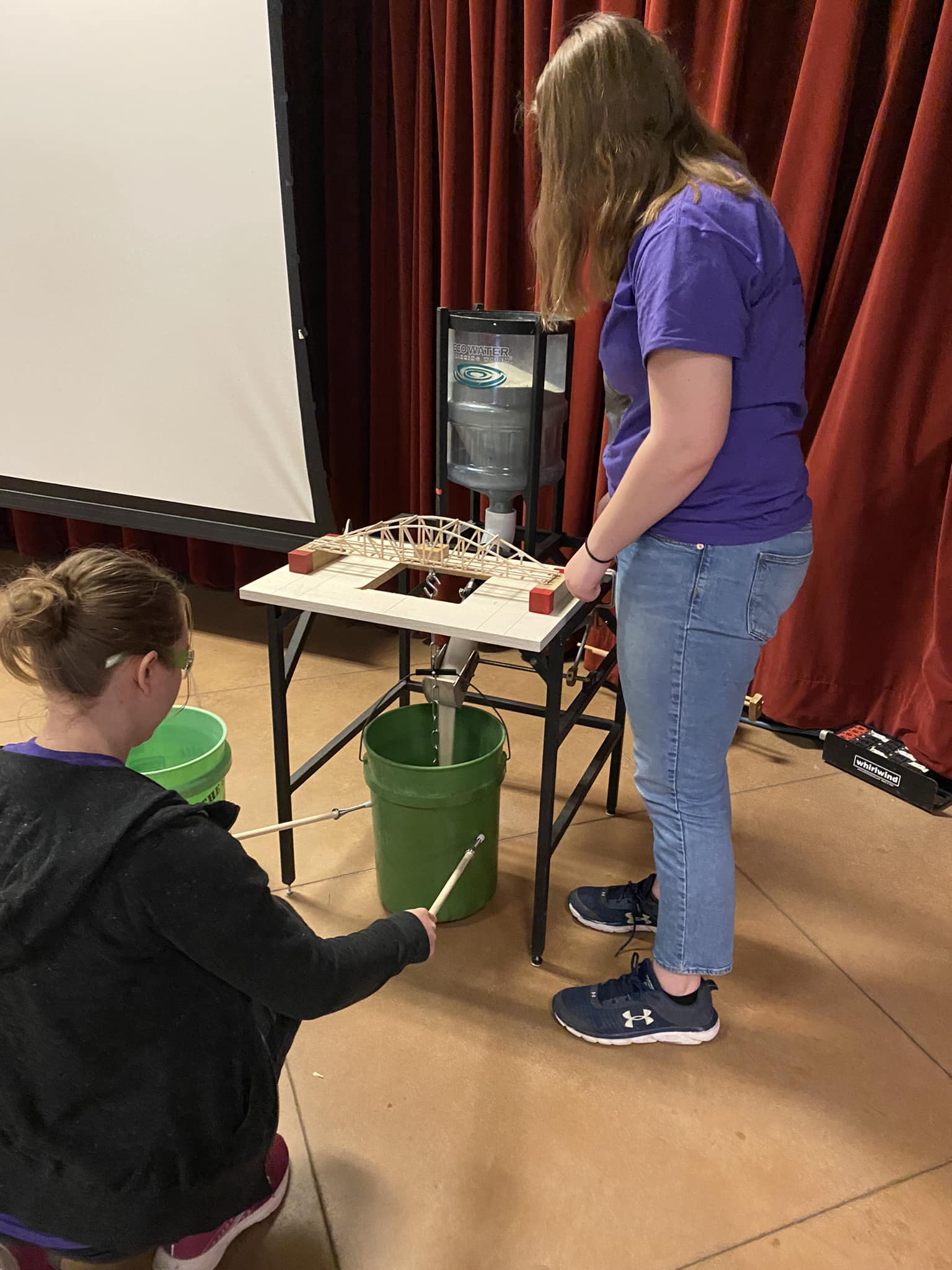 Hattie and Amanda testing their bridge. - HHS Science Olympiad | Facebook