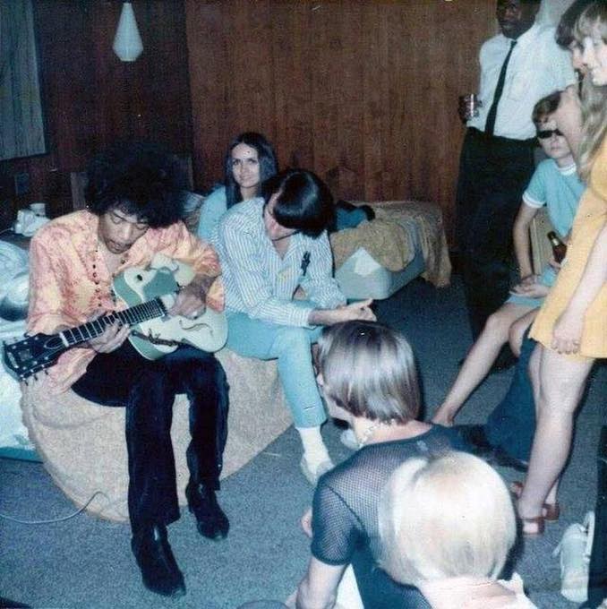 Jimi Hendrix playing guitar in a hotel room with Michael Nesmith
