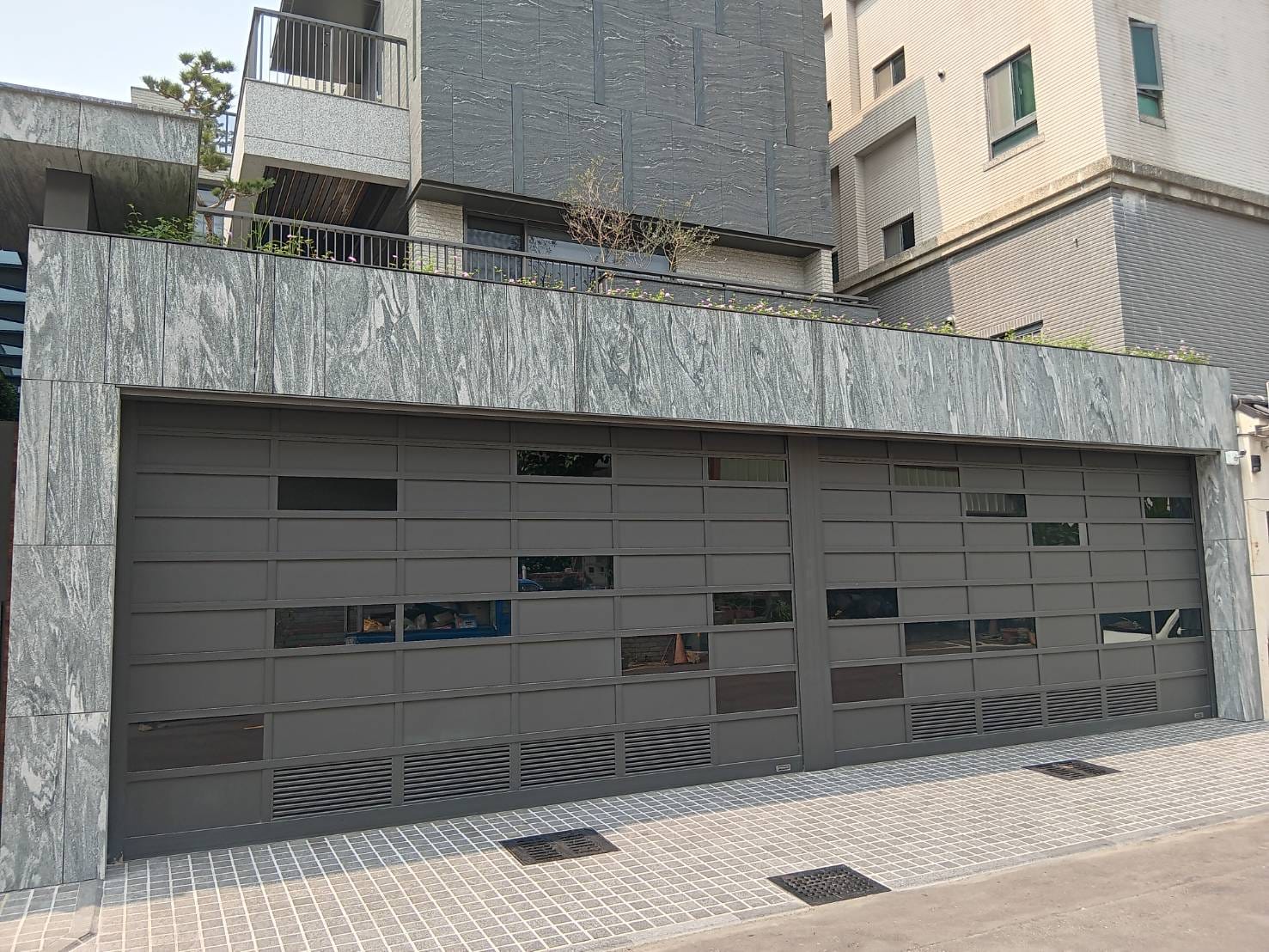 福麗門實業 - 位於台中市西屯區的案場 捲門選擇用鋁板及黑色噴砂玻璃以不規則幾何方式錯落設計 下方鑲嵌百葉增加通風性... | Facebook