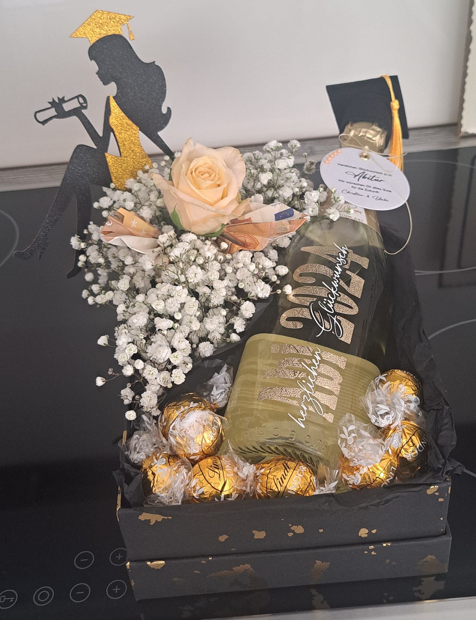 Geschenk zum Abitur. Sekt-Flasche mit Text beplottet, Blätter der Rose aus Geld gefaltet