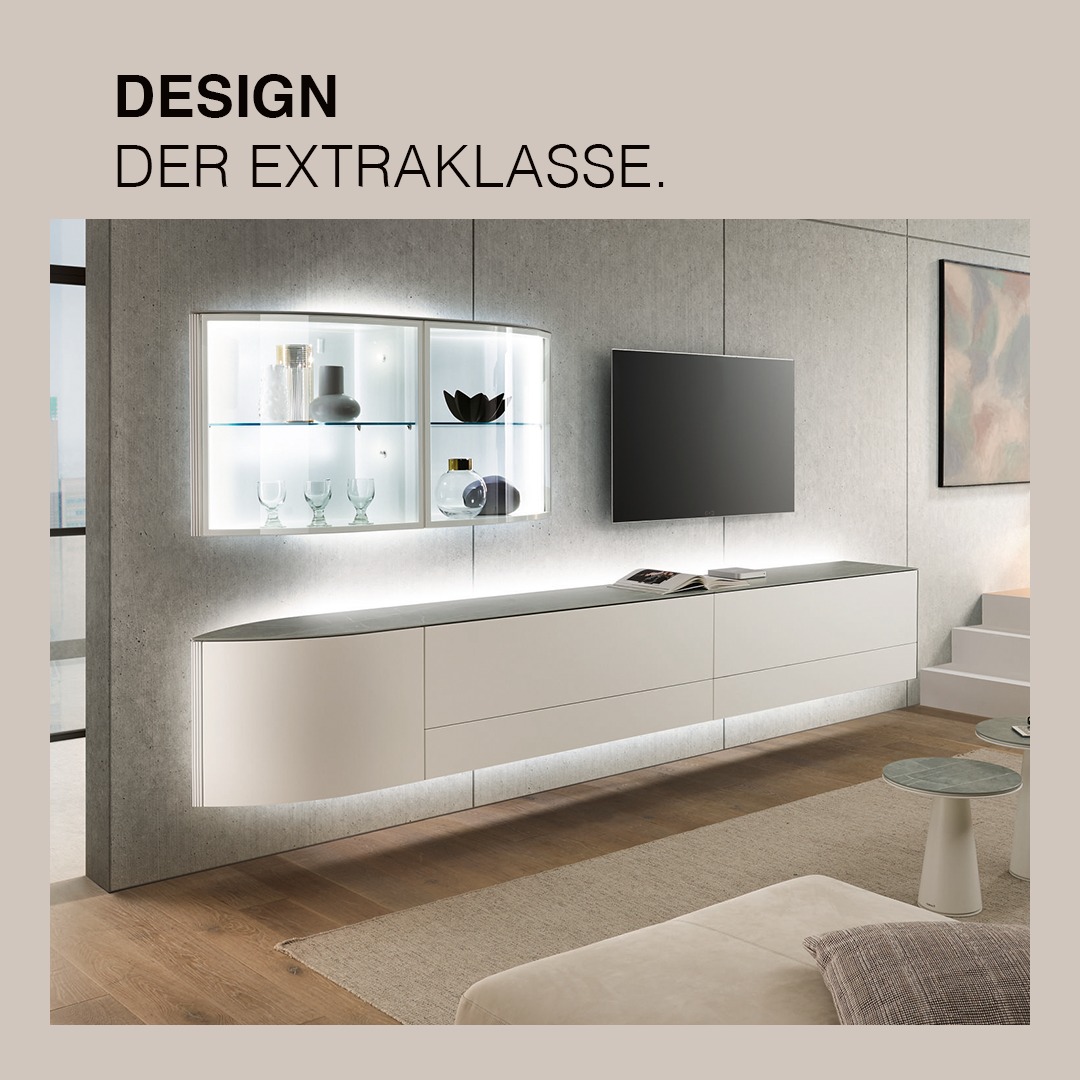Ästhetik in Weiß: Die hülsta Navis Wohnkombination mit Sideboard und Vitrinen-Hängeelement veredelt mit der zeitlosen Eleganz von Keramik Zaha Stone. Ein harmonisches Zusammenspiel von Design und Funktionalität, das jeden Raum zum stilvollen