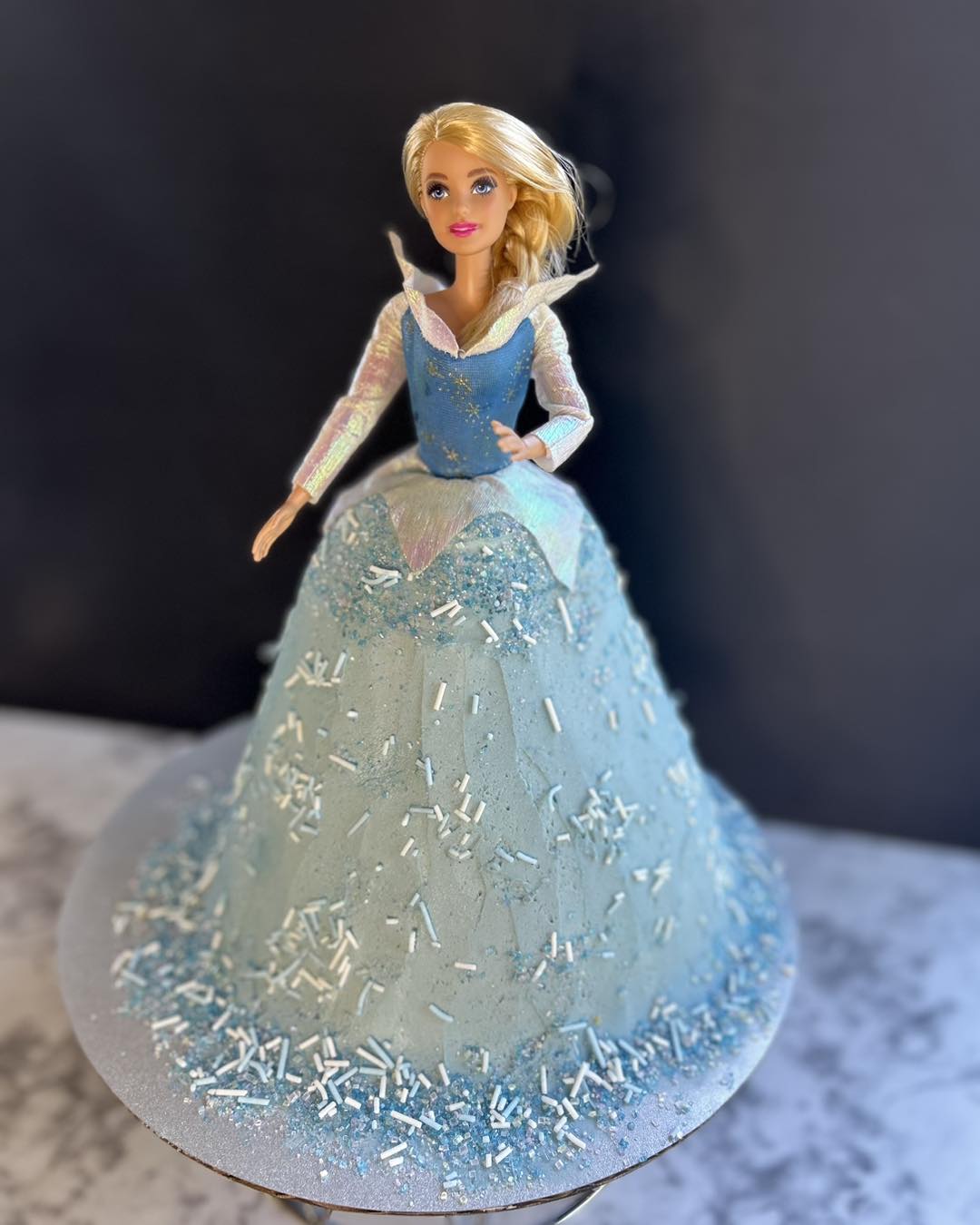 glitter dress cake ❄️🍰 'Elsa' Barbie made with vanilla and filled with sprinkles! ❄️🍰 #elsacake #frozencake #elsabirthday #vanillacake #vanillabuttercream #packedwithsprinkles #cakesofinstagram#cake#localbusiness#instayum#cakeisart#freshisbest#lovecake upload-20260622