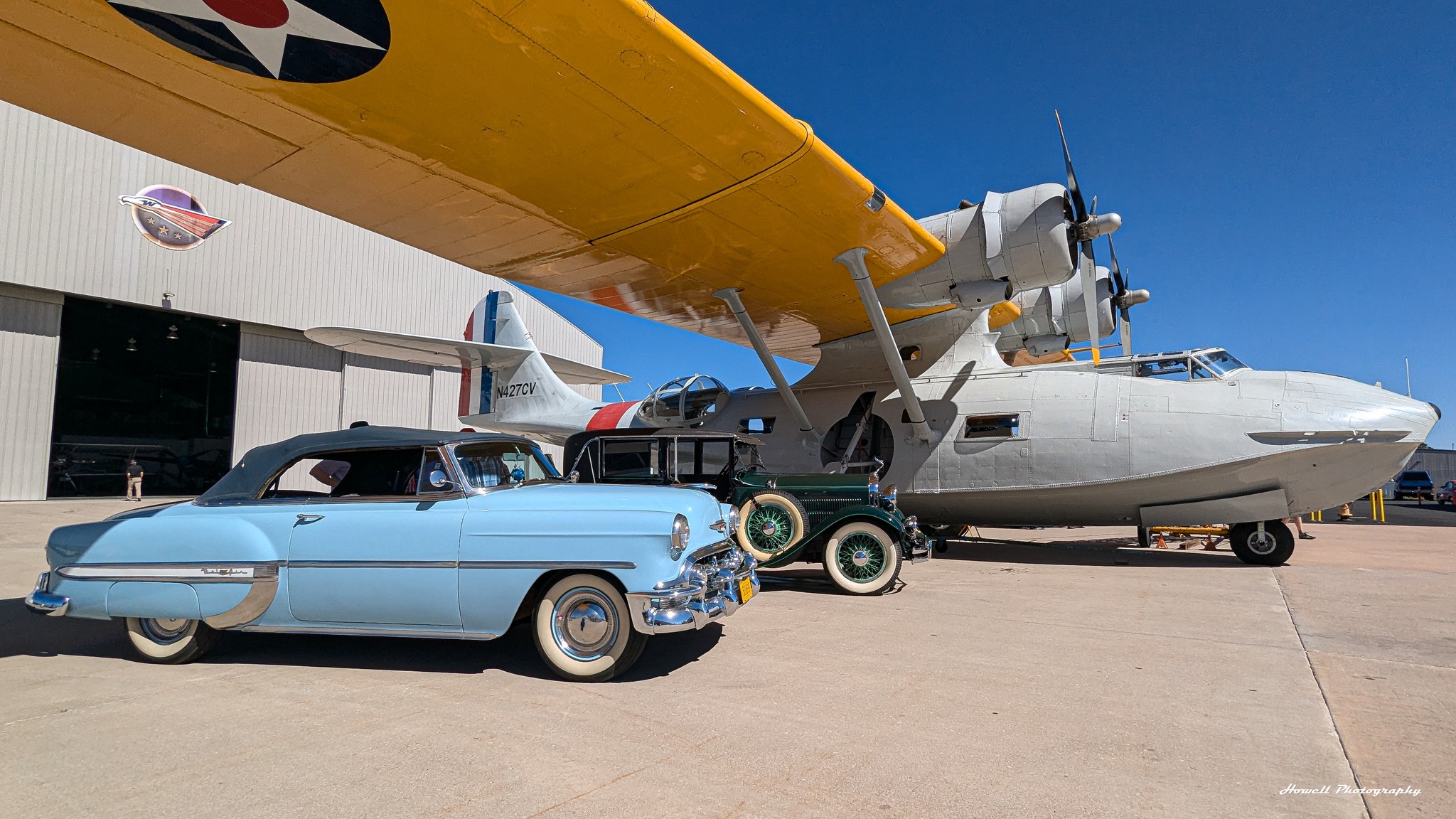 National - The broad wing of our PBY Catalina shelters two vintage cars ...