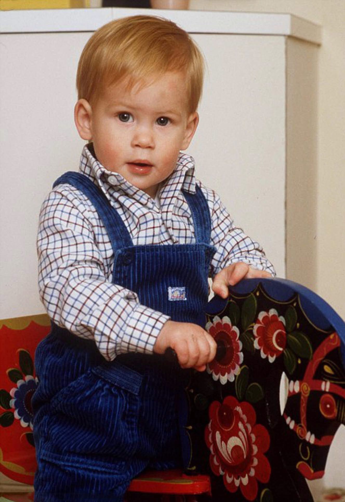One-year-old Prince Harry sitting on a rocking horse in the