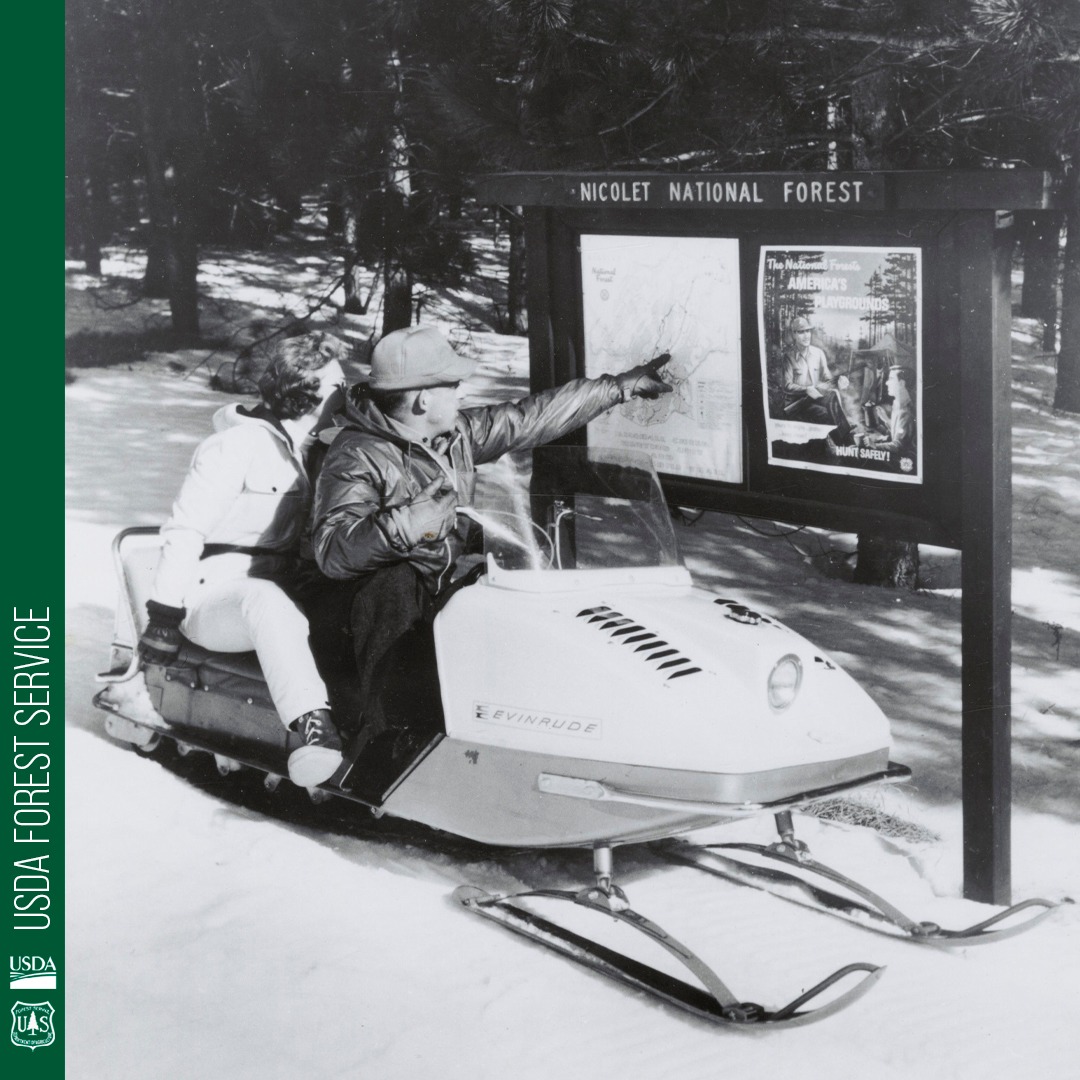 U.S. - A couple on a snowmobile check their way with a forest trail map ...