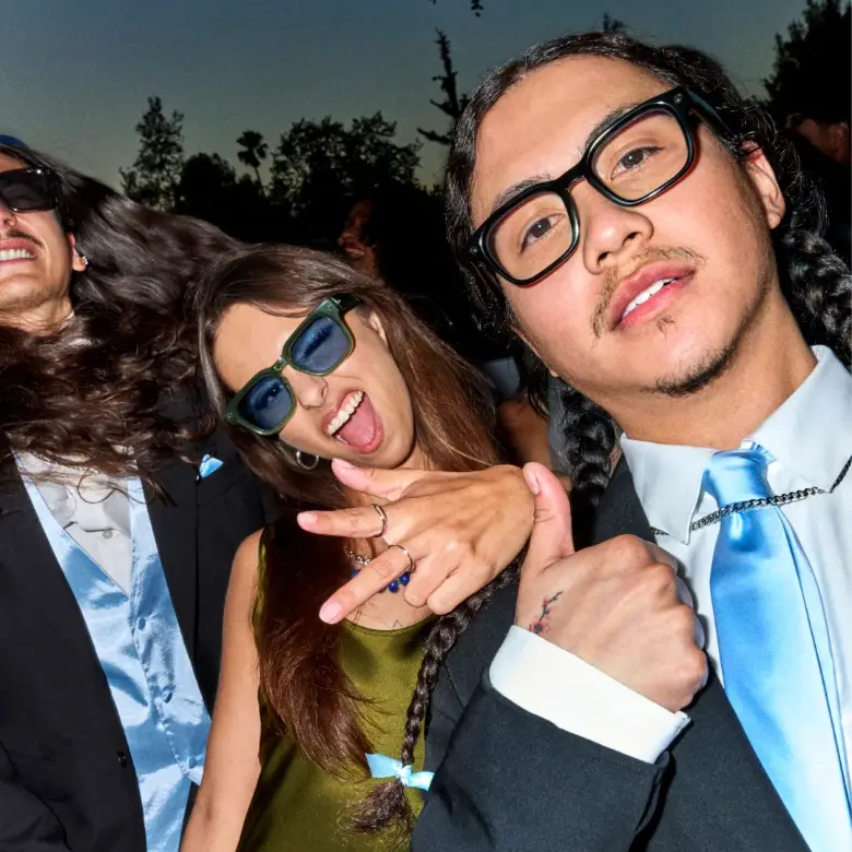 Um grupo de amigos vestidos formalmente, com ternos, gravatas e óculos inteligentes, juntos ao ar livre ao anoitecer