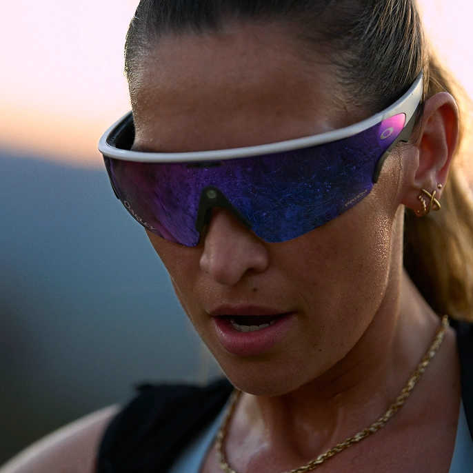 A woman exercising and wearing purple Oakley Meta Vanguard glasses at sunset.