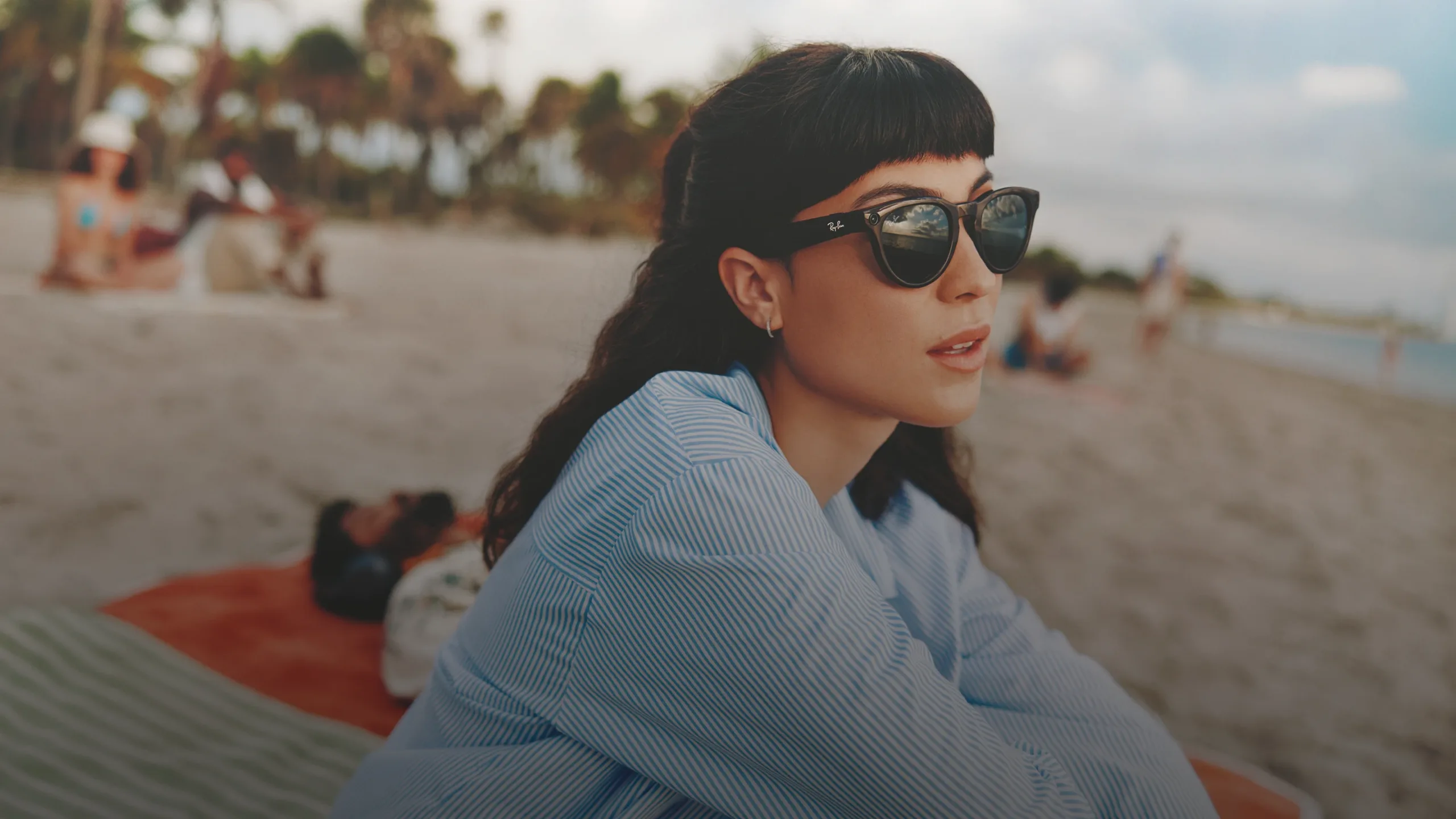 Person relaxing at the beach wearing Ray-Ban Meta Wayfarer sunglasses with Shiny Black frame and G15 lens.