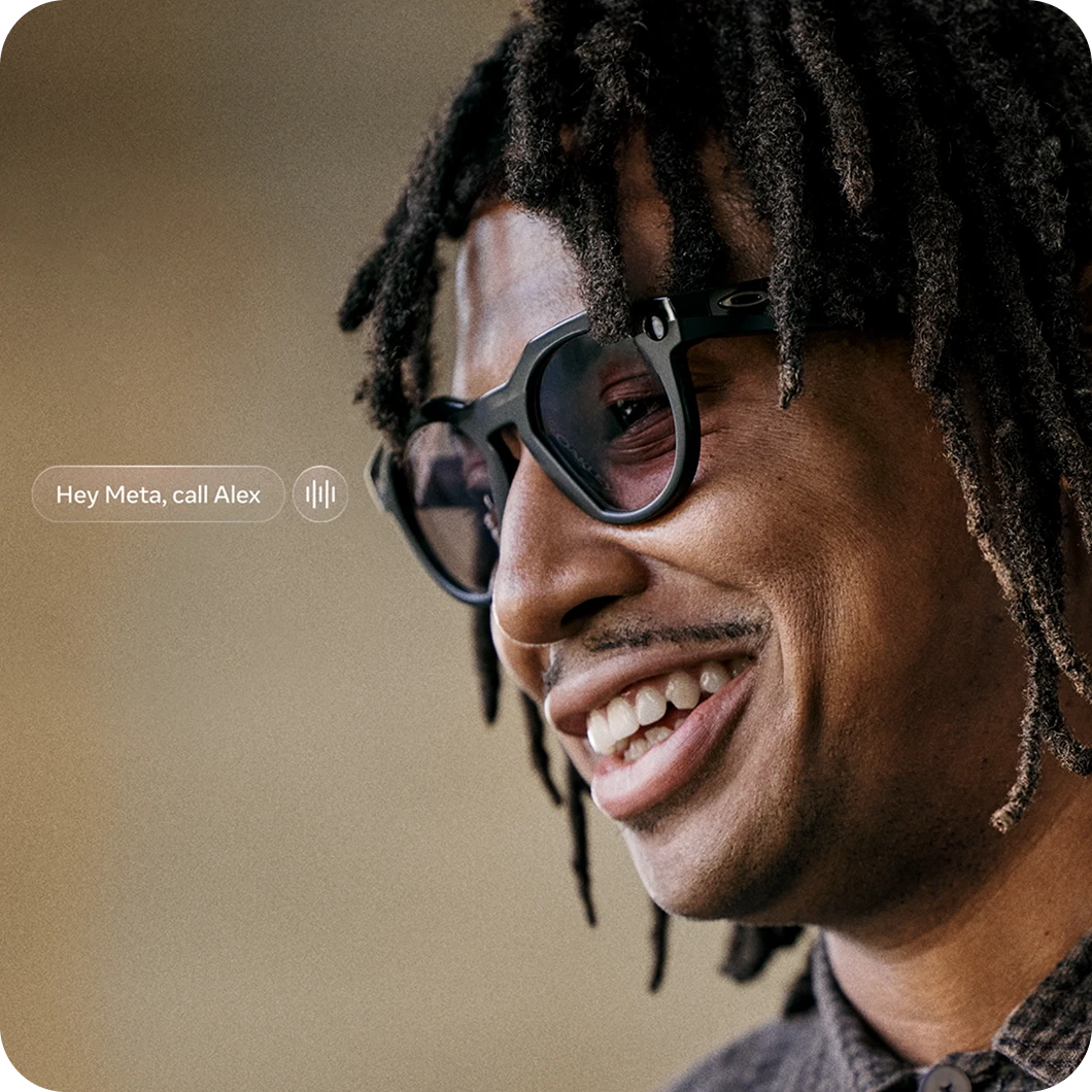 With text that reads "Hey Meta, call Alex". Close-up of person smiling in Ray-Ban Meta Wayfarer sunglasses.