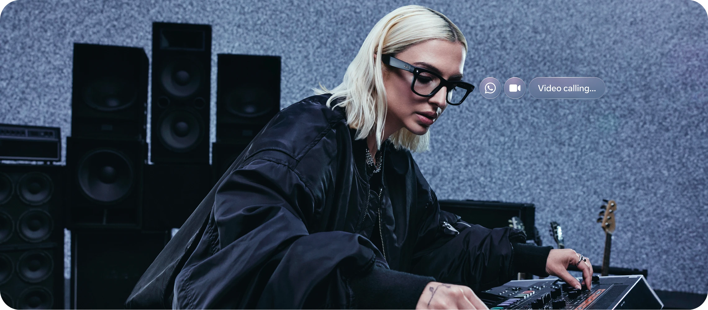 Person at a DJ console takes a hands-free video call in Ray-Ban Meta Wayfarer glasses with clear lens.